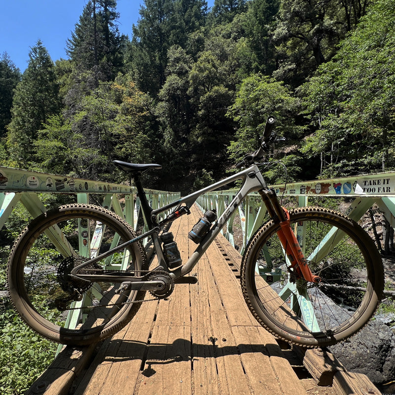 A mountain bike on a foot bridge with green trees in the background