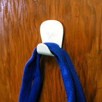 S.R. Anywhere Hook in Matte White on a wood wall holding a blue handle