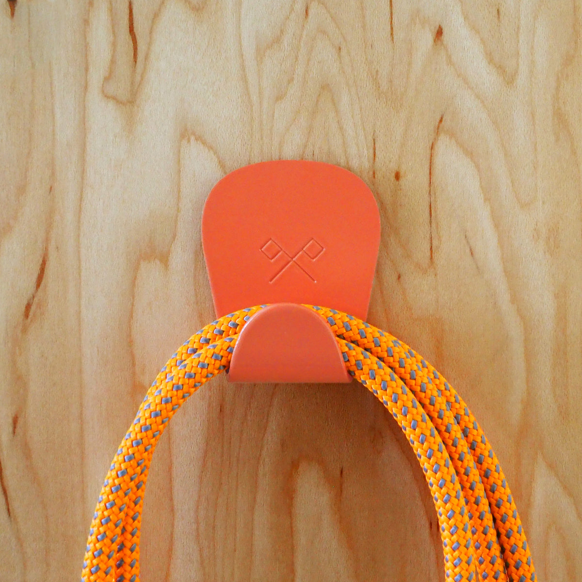 S.R. Anywhere Hook in Salmon Pink on Wood wall holding bright orange and grey paracord.