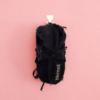 Matte white S.R. Wall Hook holding a black backpack on a pink background.