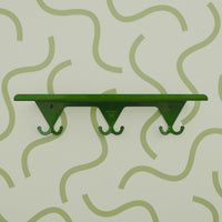 Fern Green S.R. Wall Rack on a light green background with green squiggly lines.