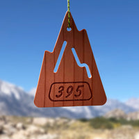 The S.R. Air freshener shaped like a mountain with "395" etched on the bottom. Background of mountains and blue sky.