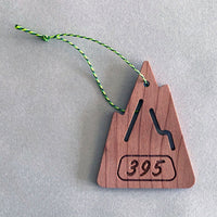 A mountain shaped S.R. Air freshener made of wood and bright paracord for hanging on a grey background.