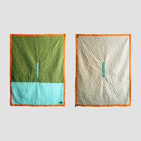 Blanket silhouette showing the front of the SR Anywear Blanket with Green and Mint on the left and off white on the  right