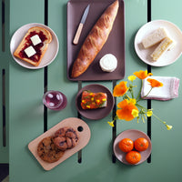 Overhead view of a pale green S.R. All Aluminum Table Set with pastries, fruit, and bread on the table top with a vase of orange flowers.