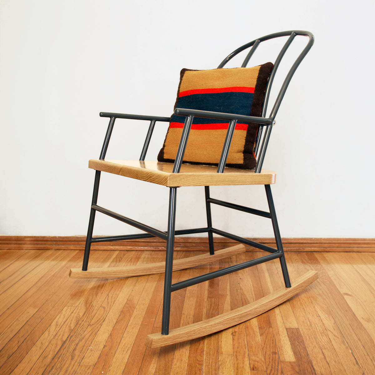 A Navy Gray S.R. Rocker with a striped pillow in a room with white walls and hardwood floors.