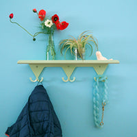 Mint Green S.R. Wall Rack with vases of flowers on the shelf. Navy jacket and turquoise link necklace hanging on the hooks.